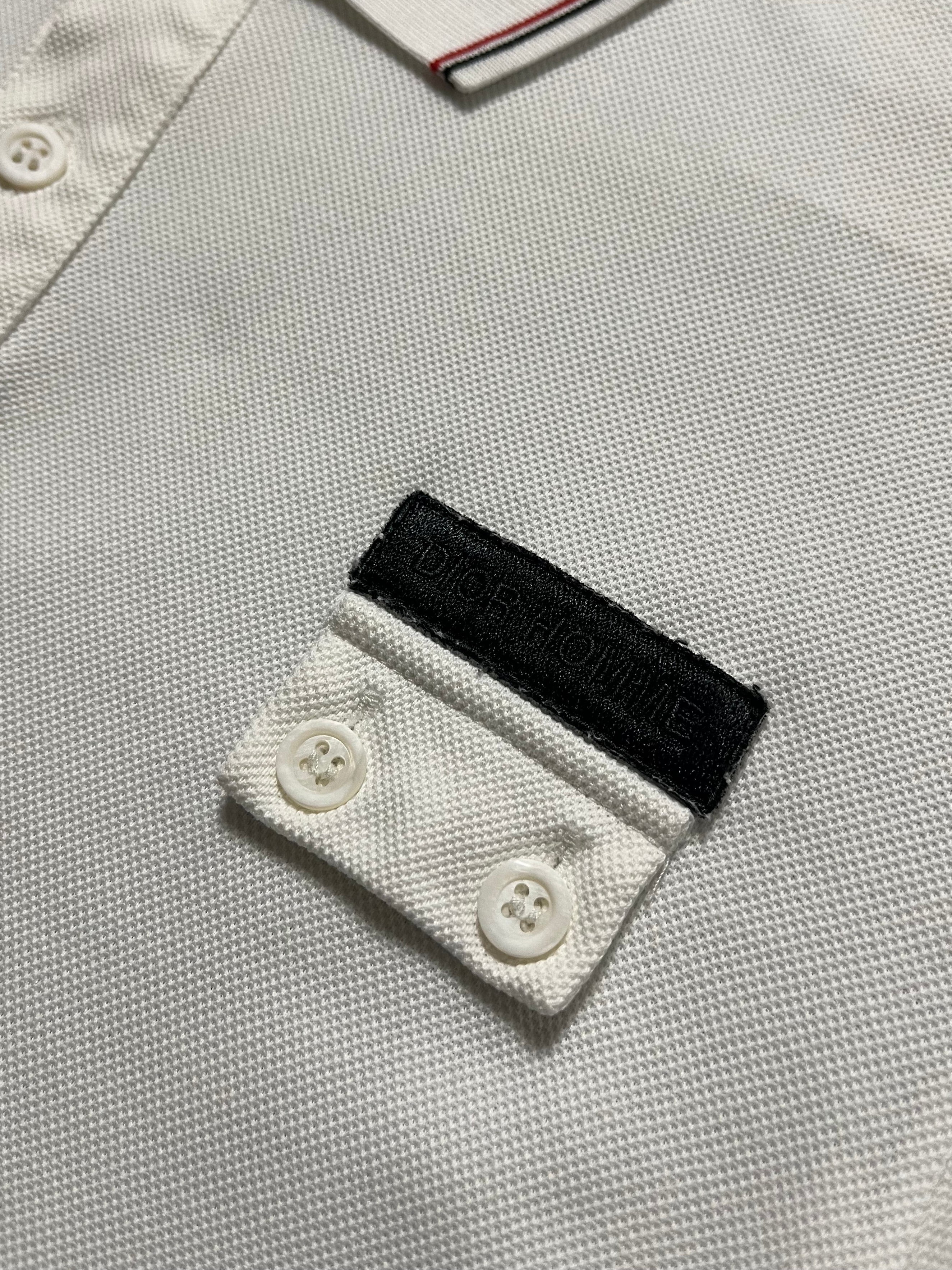 Dior SS07 Patch Polo in navy with colorful embroidered patches, classic polo collar, and short sleeves on a white background.