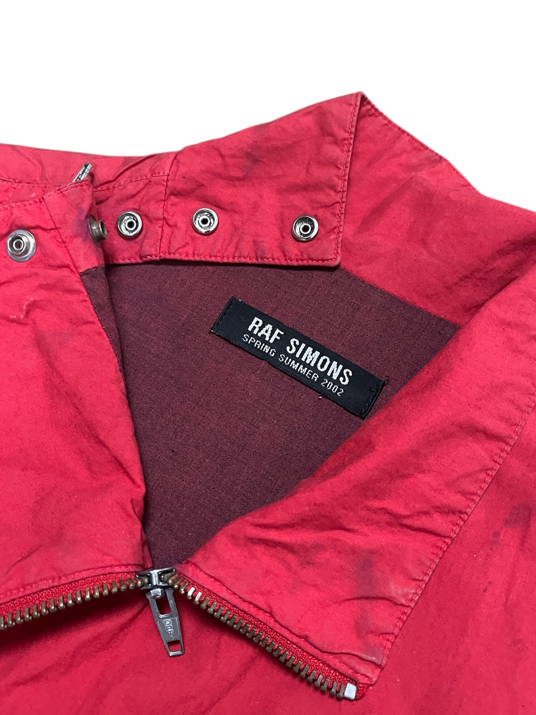Red Raf Simons SS02 "Woe Onto Those" boiler suit, coverall style, with front zipper and utility pockets, casual and edgy fashion piece.