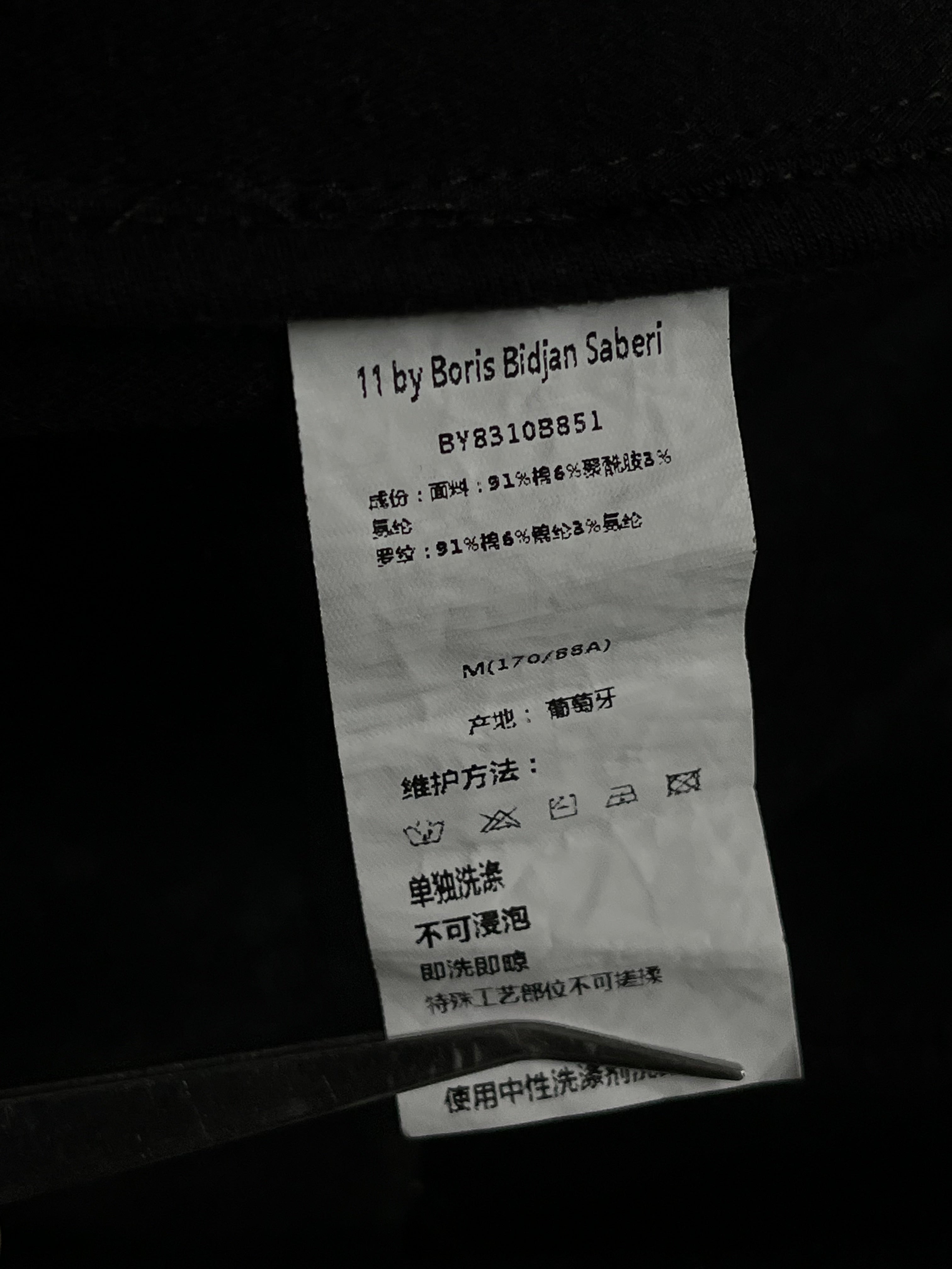 Black Boris Bidjan Saberi Ninja hoodie with layered, textured design and hood, displayed on a mannequin.