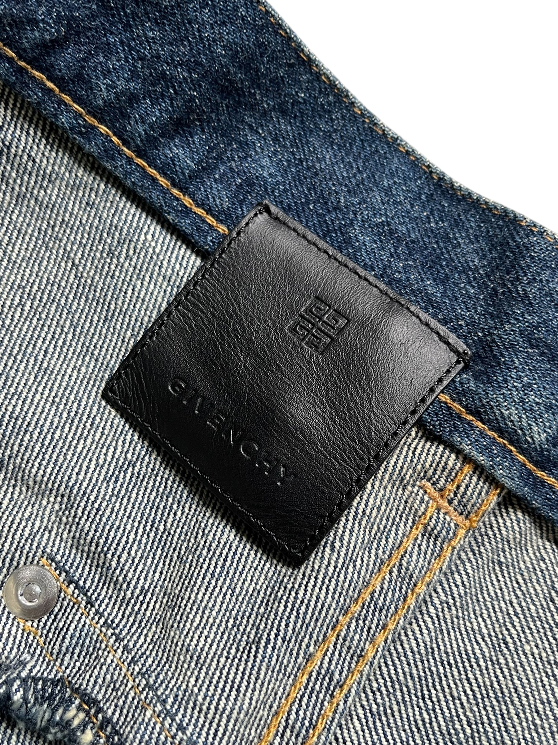 Givenchy FW23 distressed boro blue denim pants with ripped details and a relaxed fit, styled for casual wear.
