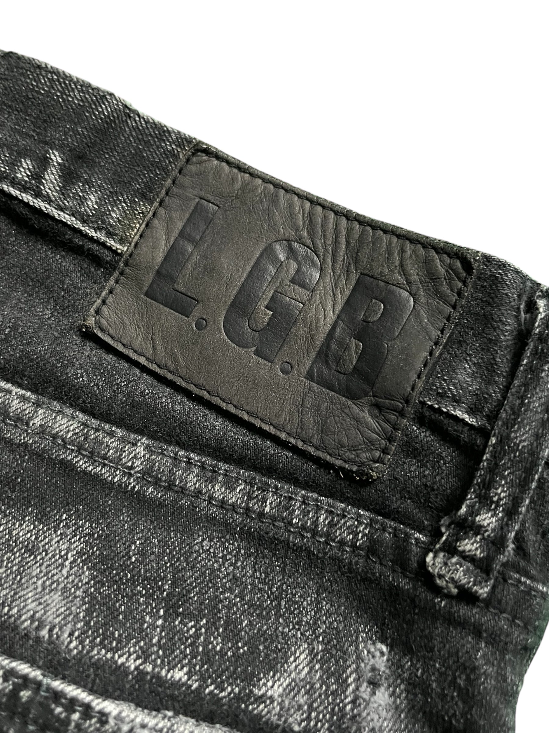 Le Grande Bleu wolf cut waxed distressed denim pants showing ripped details and a fitted style with a rugged finish.