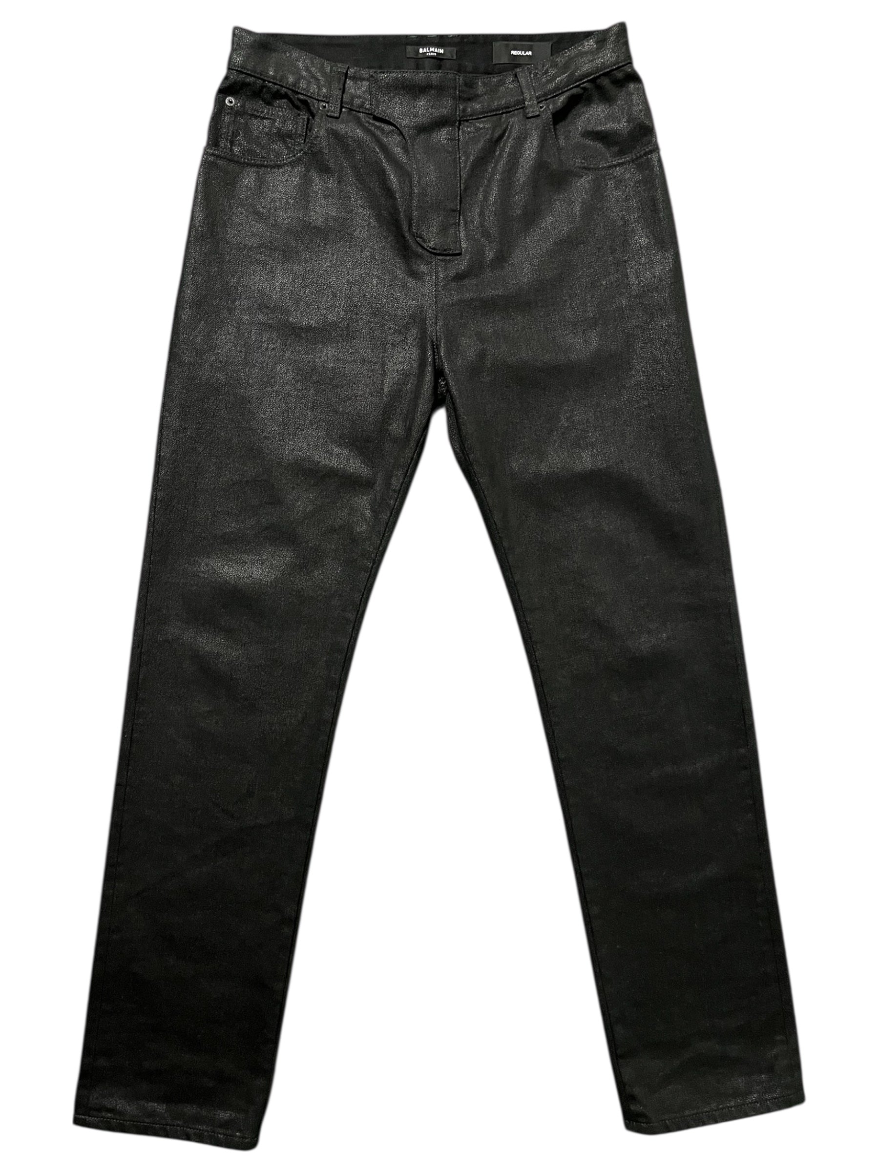 Balmain AW23 limited edition waxed denim pants showing fitted design and detailed stitching on dark, textured fabric.