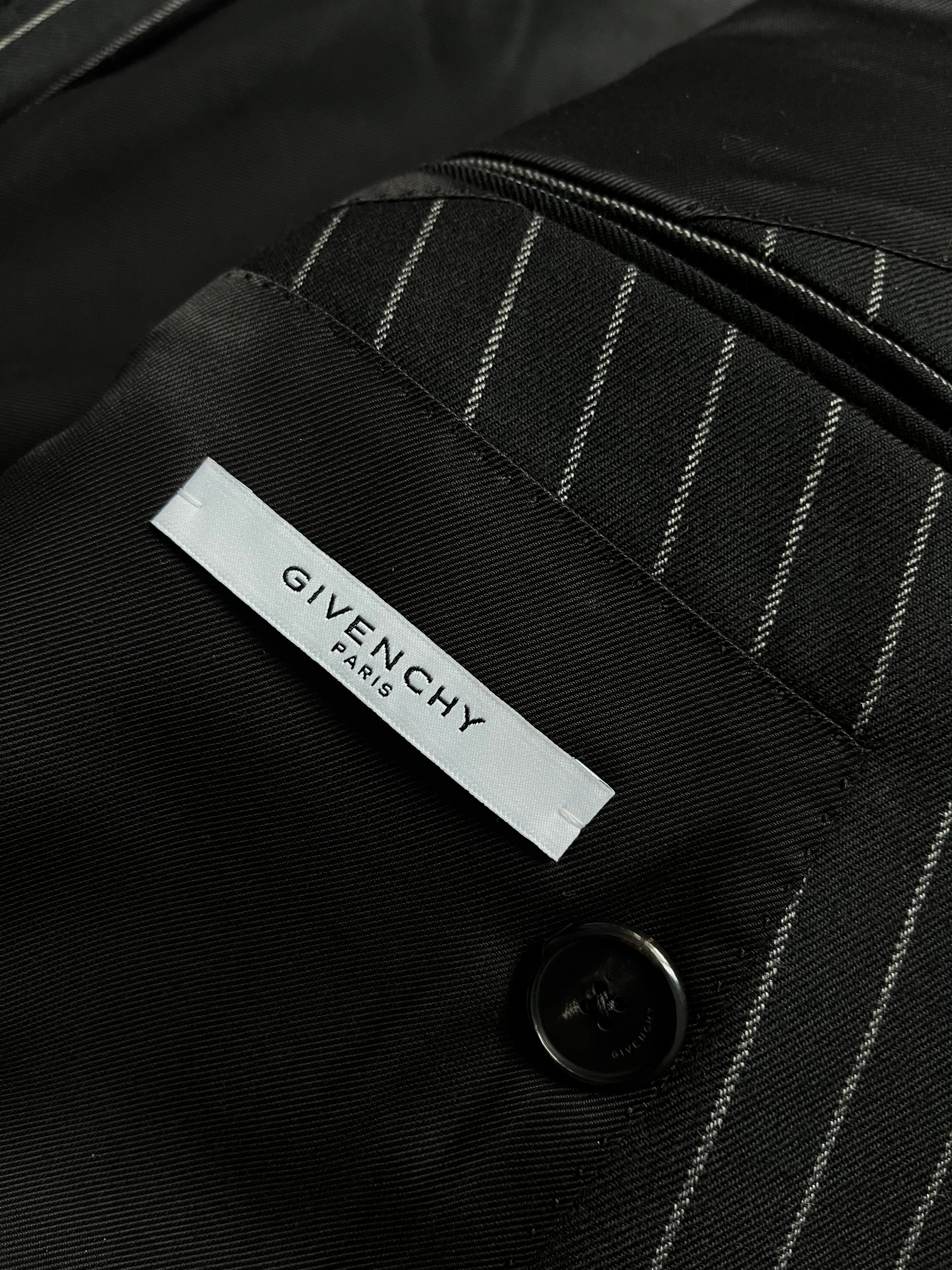 Givenchy FW15 distressed wool trench coat with a rugged, worn-in look and classic silhouette, displayed on a hanger.