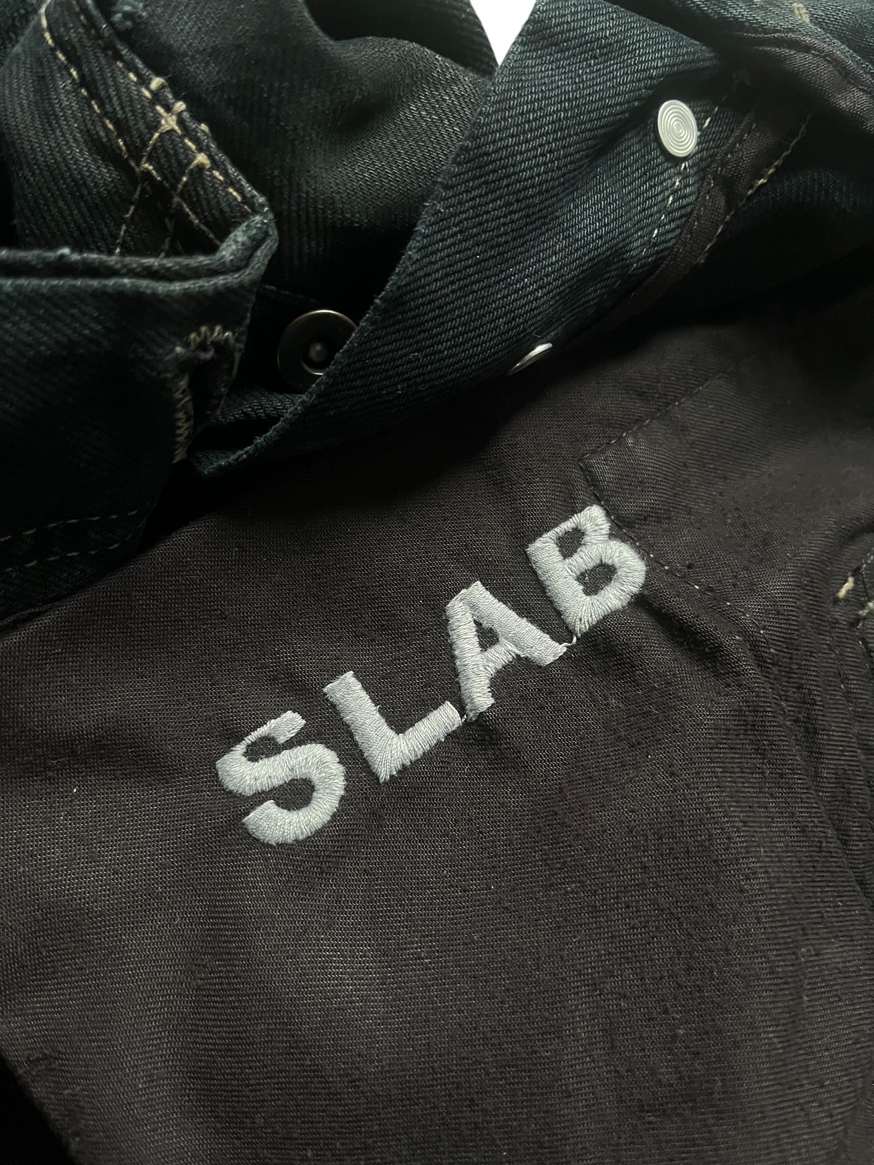 Rick Owens 2006 Slab Black Faded Denim pants with distressed details and a relaxed fit, shown on a hanger.