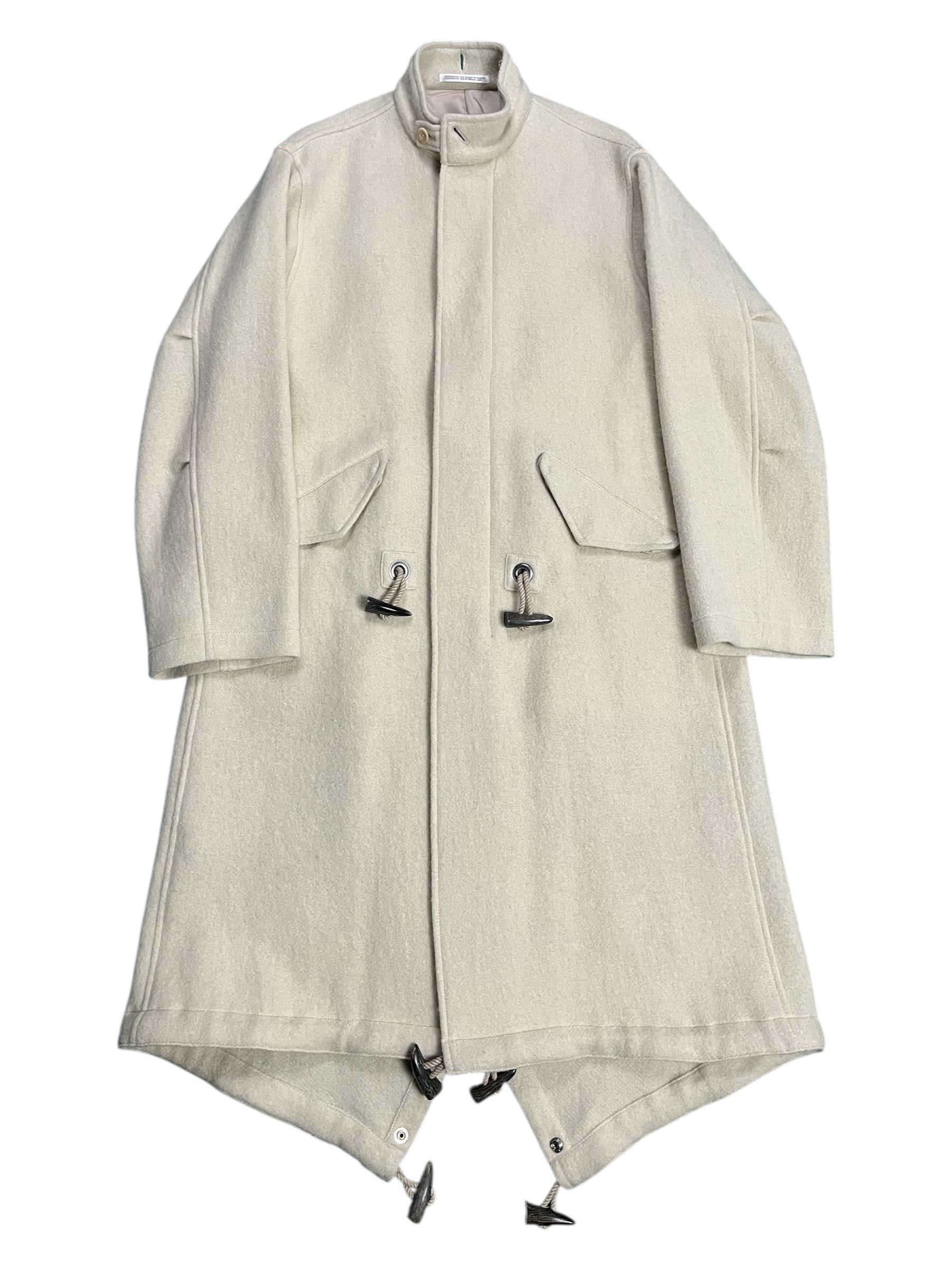 Yohji Yamamoto AW07 runway hooded wool duffel coat hanging on a clothing rack, showcasing its classic design and textured fabric.