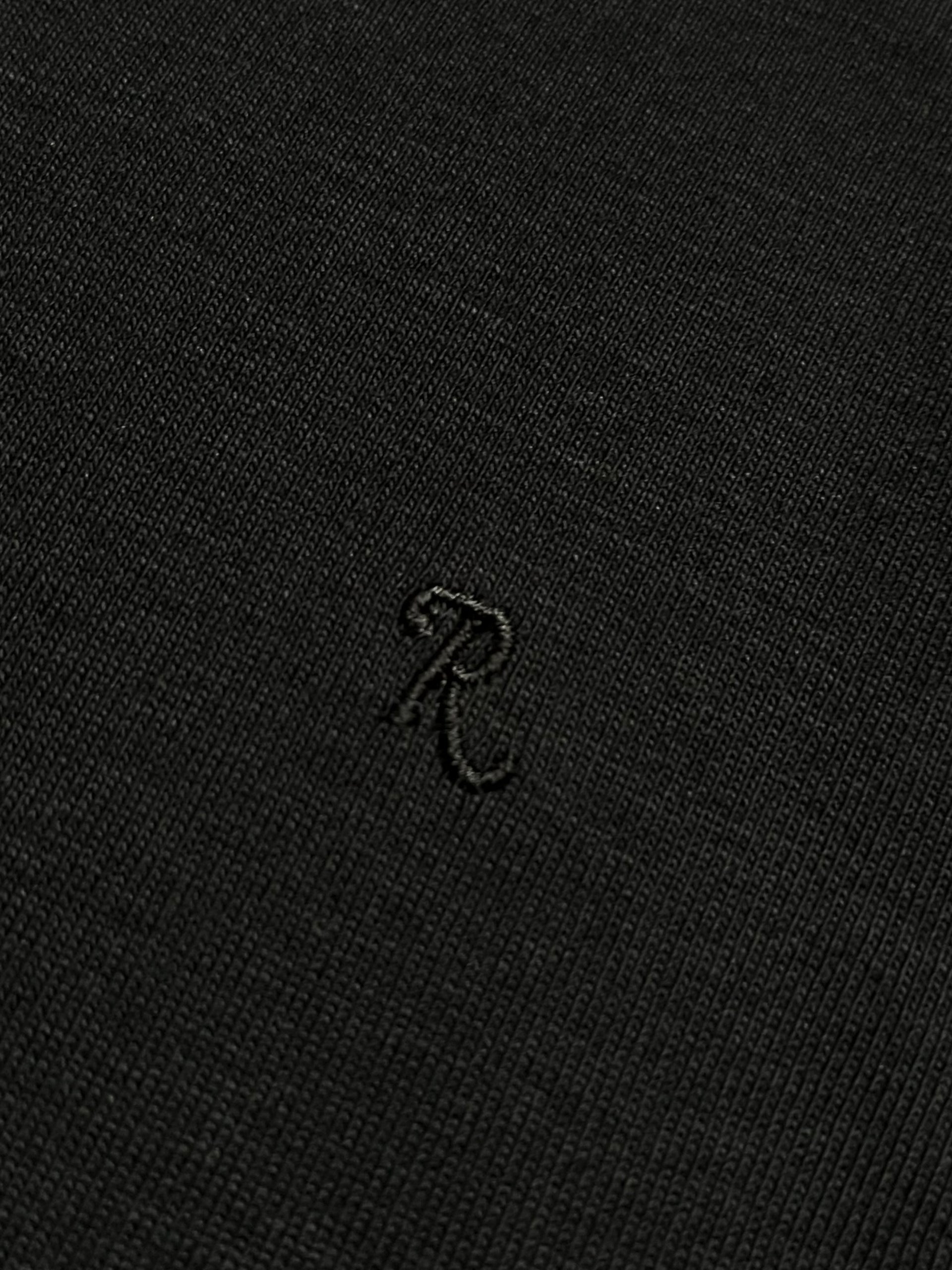 Black Raf Simons T-shirt with simple crew neckline and logo detail, displayed flat on a white background.