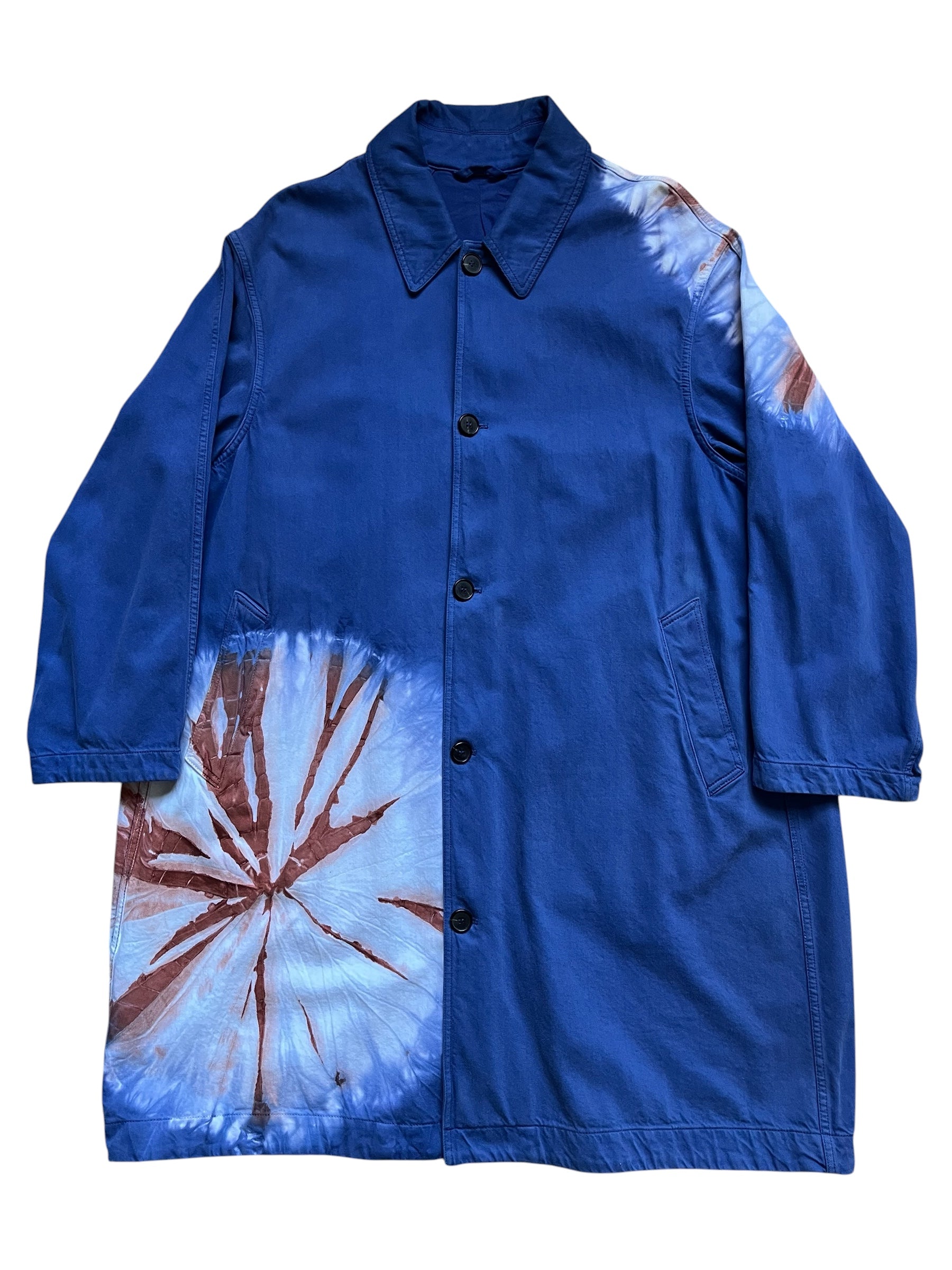 Raf Simons SS19 Calvin Klein 205w39nyc tie-dye overcoat hanging on a clothing rack, showcasing vibrant pattern and modern style.