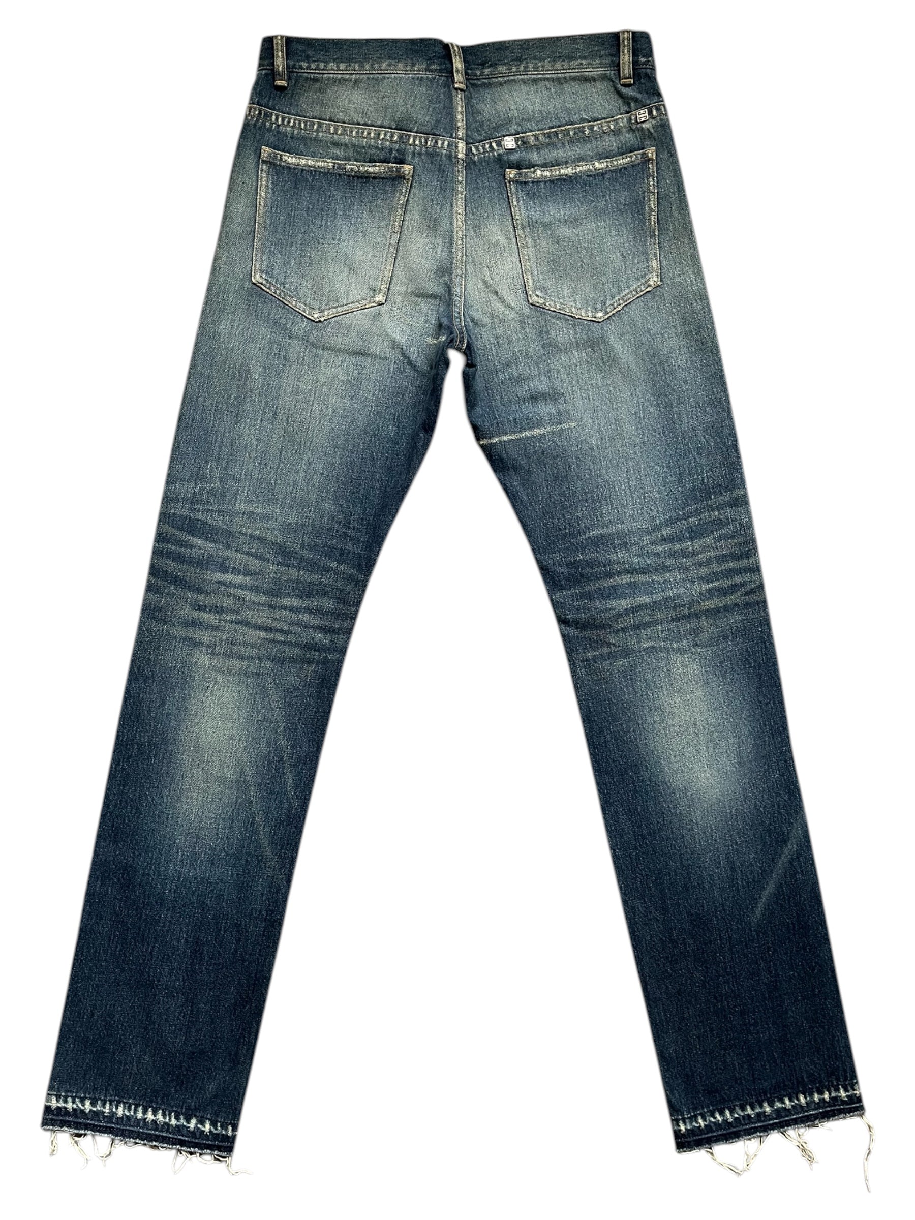 Givenchy FW23 distressed boro blue denim pants with ripped details and a relaxed fit, displayed on a neutral background.