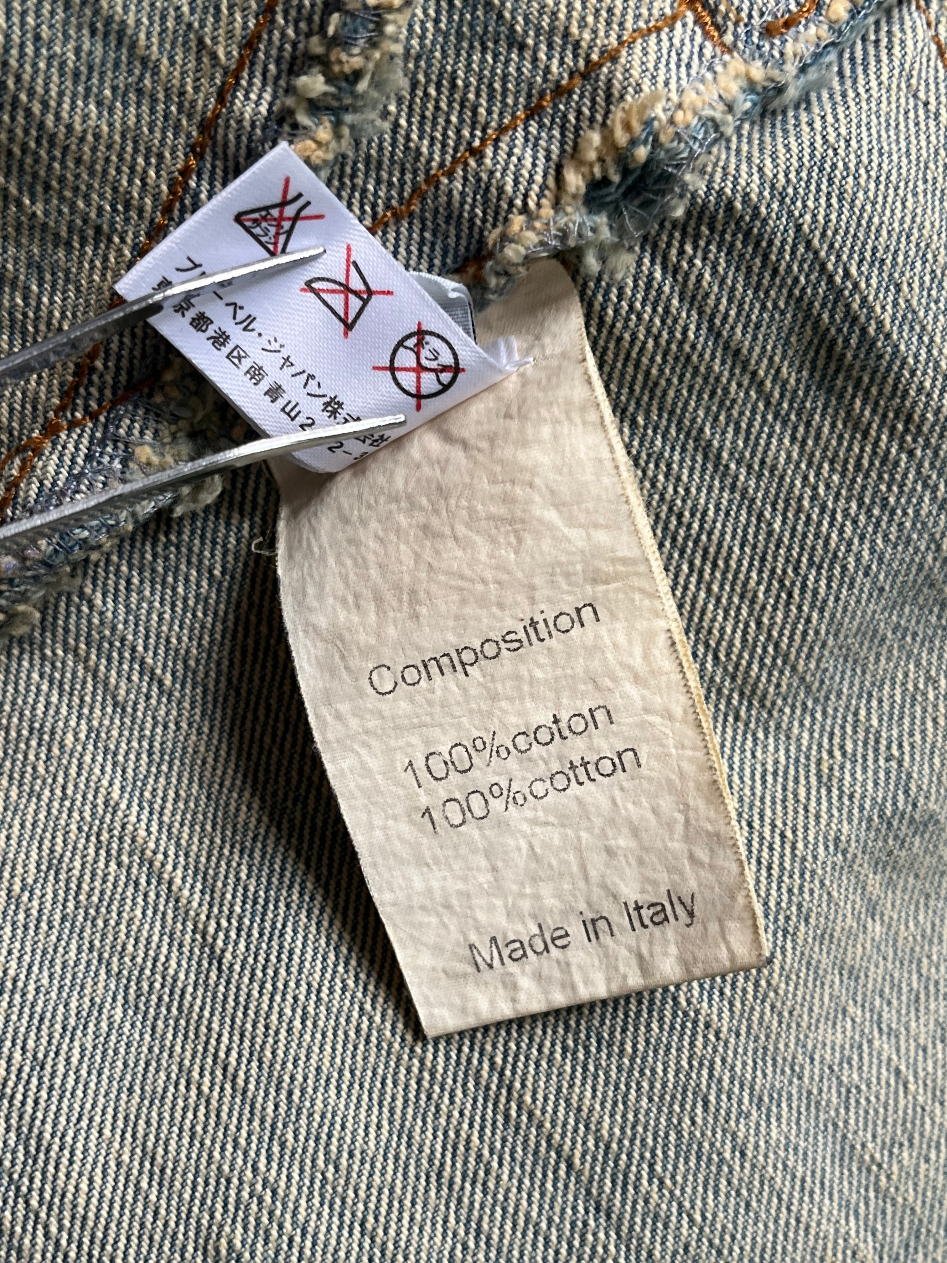 Balmain SS12 G-Dragon Mud Wash Denim Jacket displayed on a hanger, showcasing its rugged denim texture and stylish design.