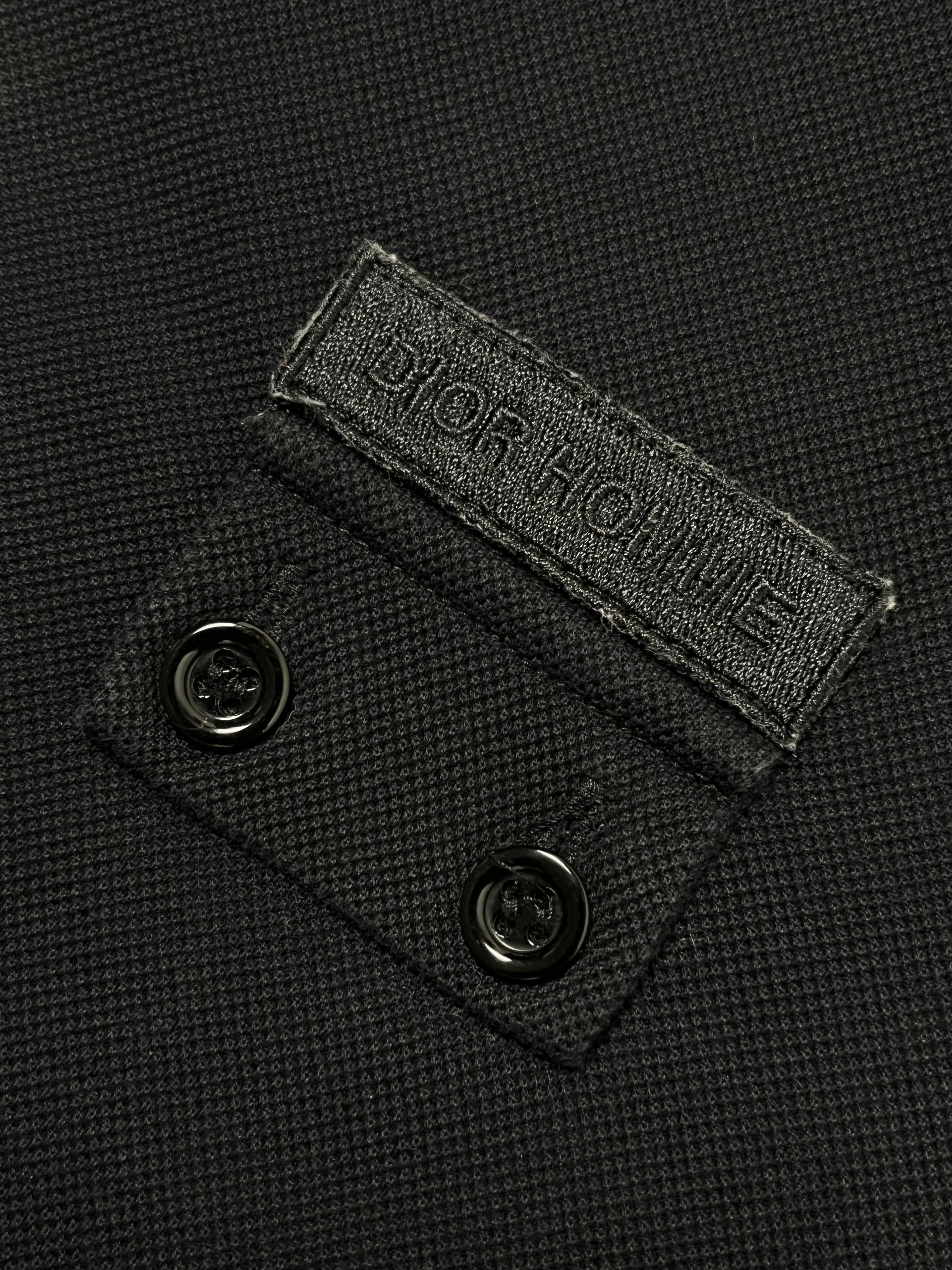 Dior SS07 Patch Polo shirt with embroidered patches, classic polo collar, and short sleeves, displayed on a plain background.