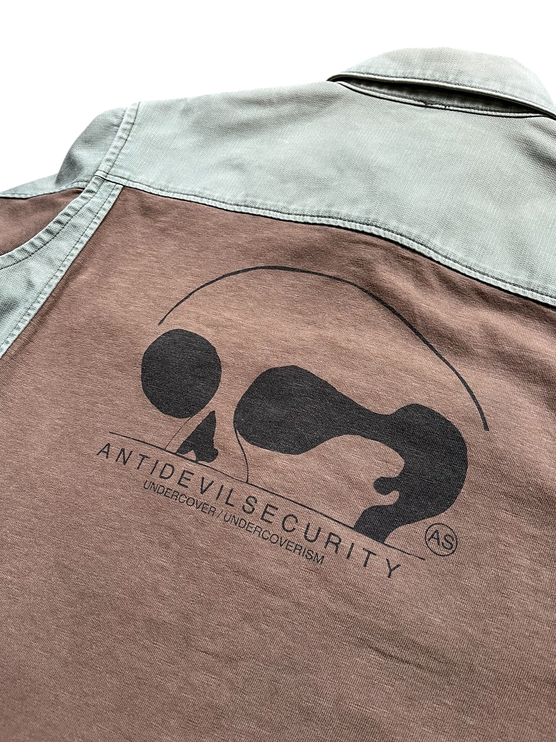 Undercover SS11 Underman Anti-Devil Military Shirt displayed on a hanger with detailed fabric and design features.