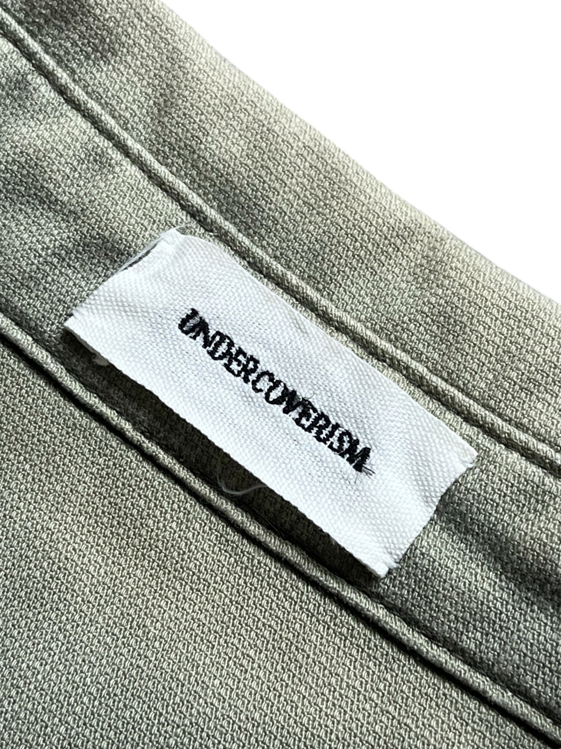 Undercover SS11 Underman Anti-Devil military shirt with camouflage pattern and tactical design, shown on a hanger.