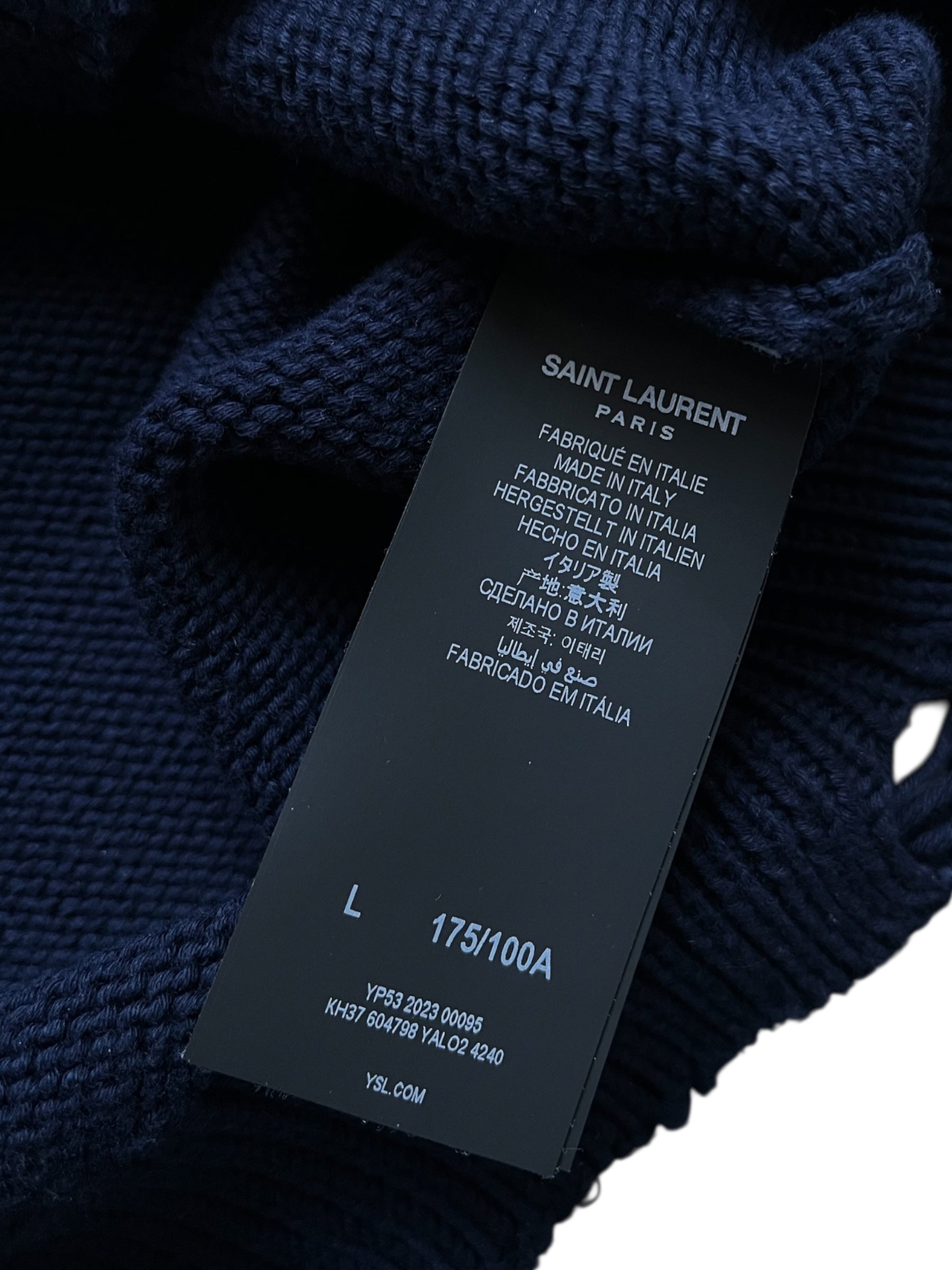 Saint Laurent AW23 distressed navy knit sweater featuring a relaxed fit and ribbed cuffs, displayed on a neutral background.