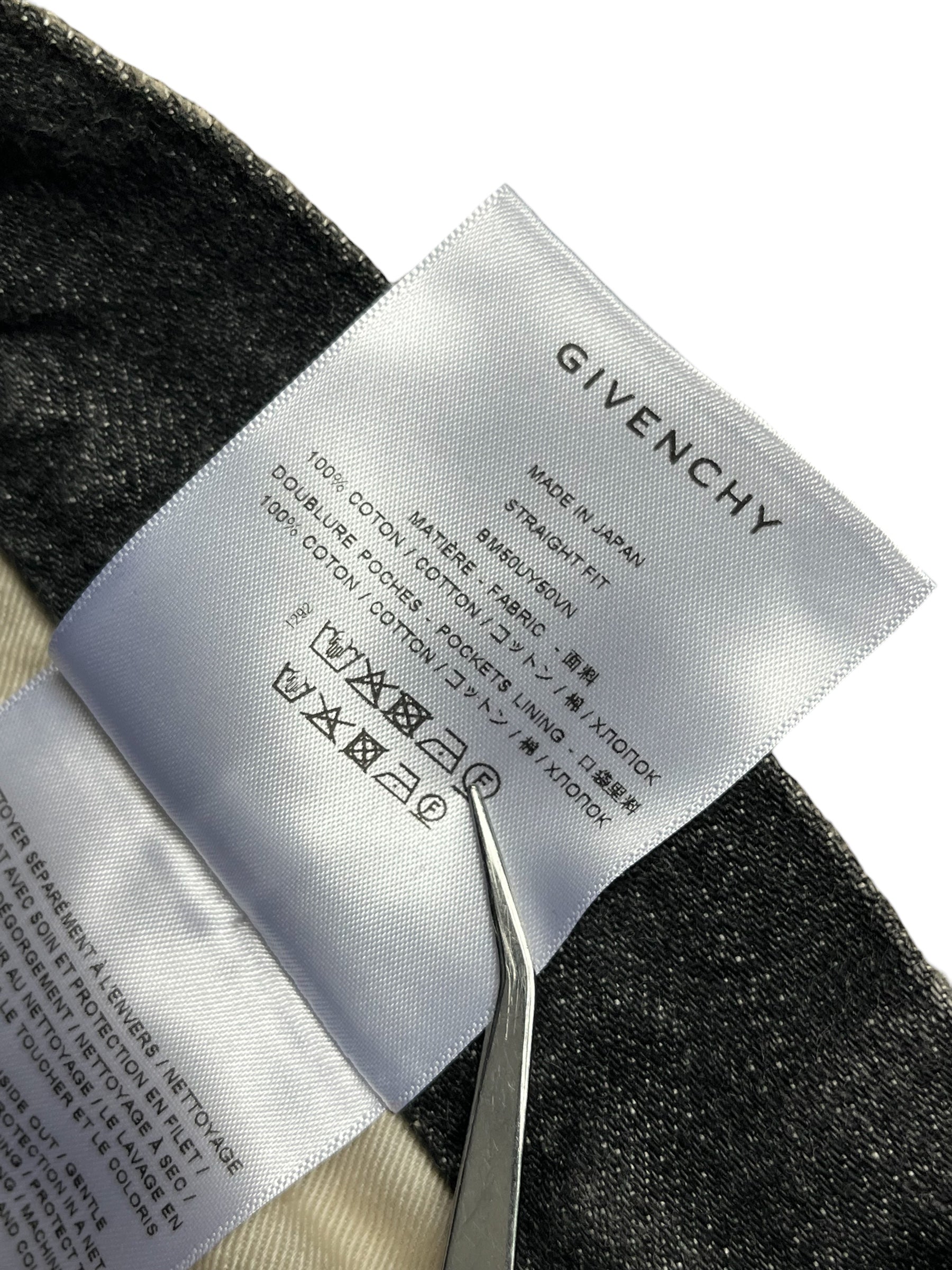 Givenchy FW23 distressed boro black denim pants with ripped details and a relaxed fit, shown on a model.