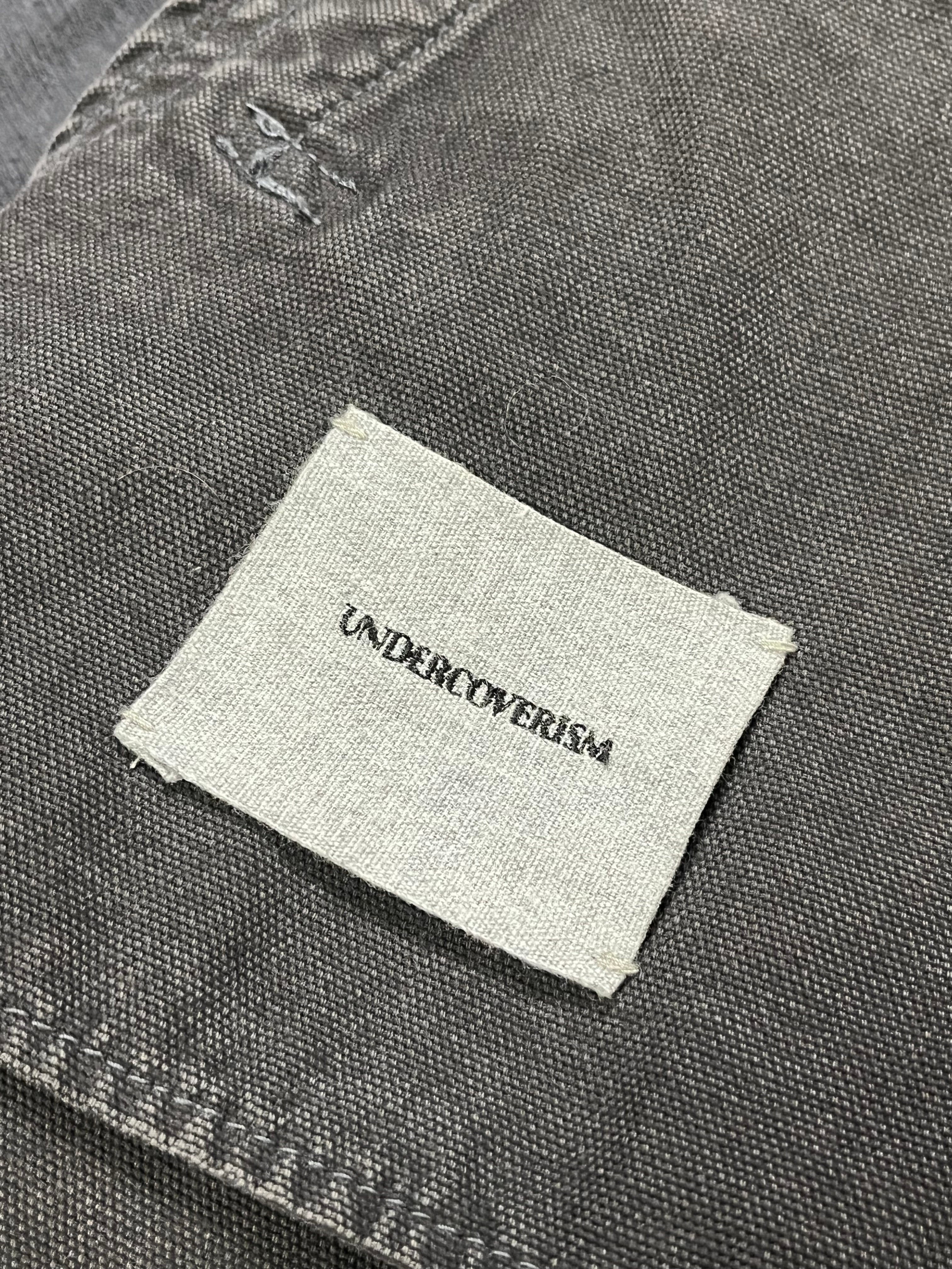 Undercover SS12 Openstrings work jacket with rugged fabric, front pockets, and adjustable straps, designed for durability and style.
