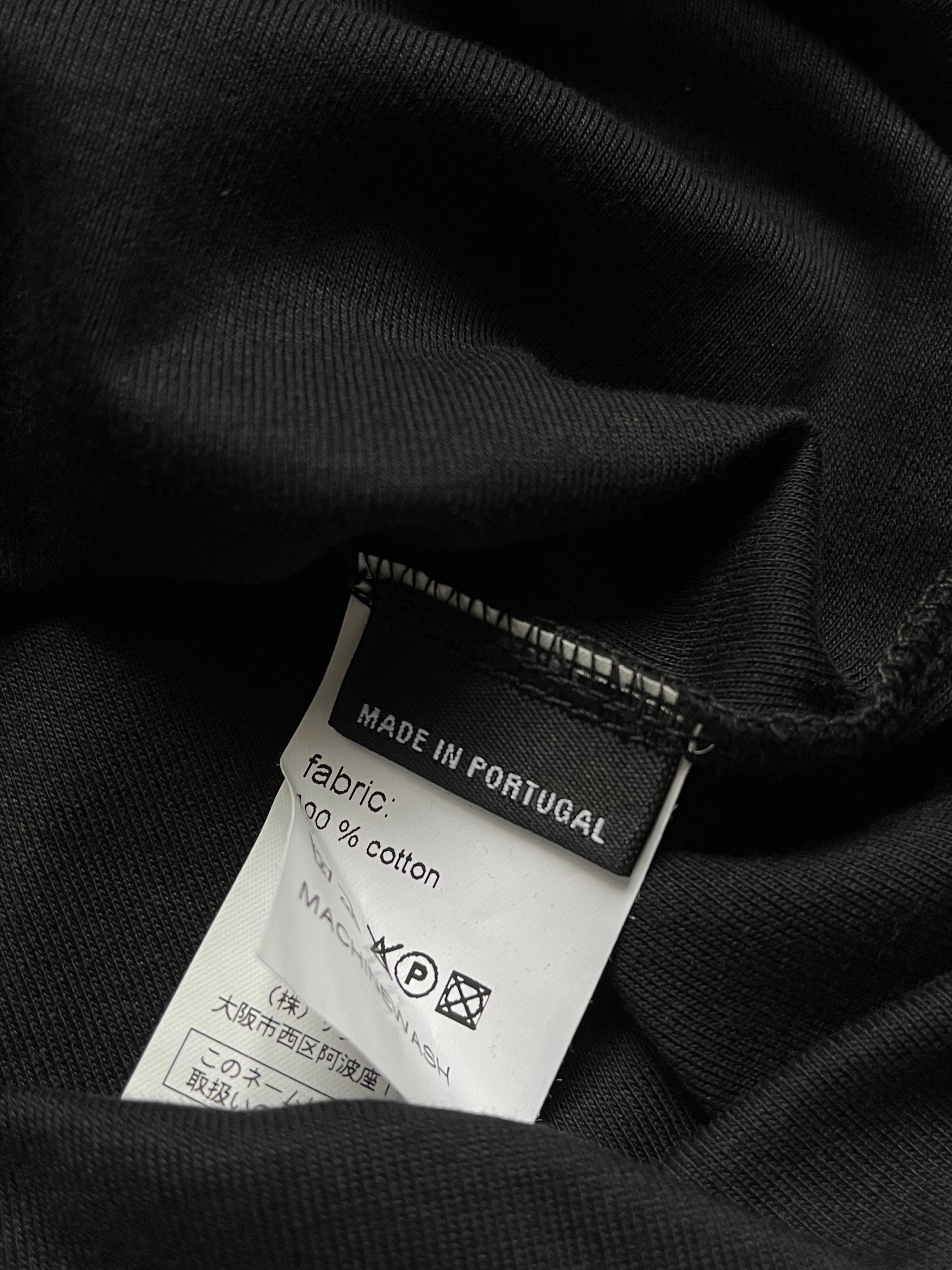 Raf Simons black T-shirt with minimalist design, featuring a crew neck and short sleeves, displayed flat on a white background.