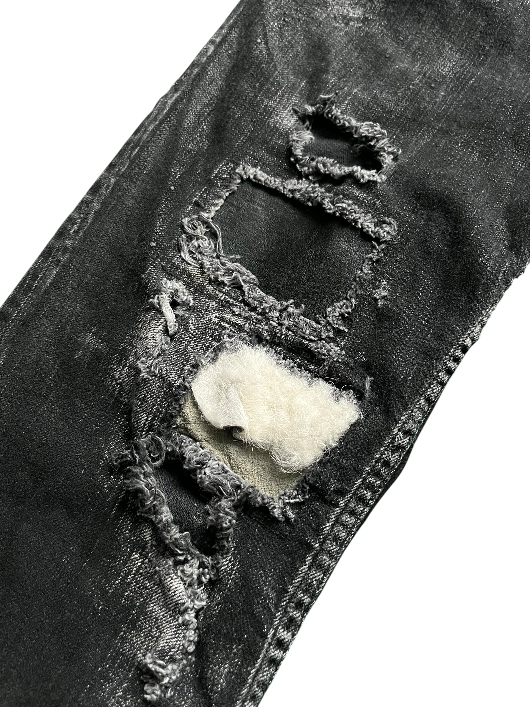 Le Grande Bleu wolf cut waxed distressed denim pants with a rugged, vintage-inspired design and distressed details.