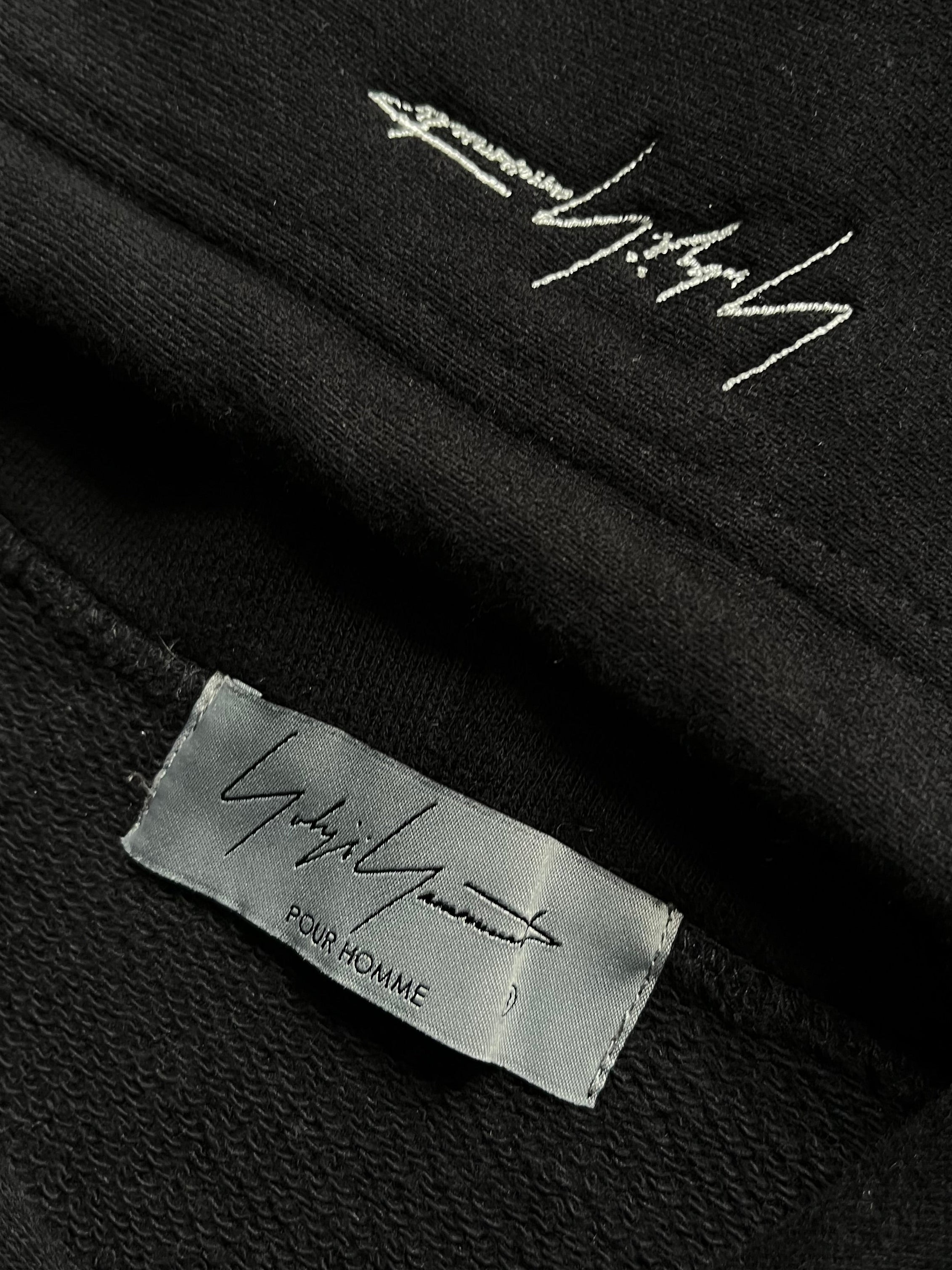 Yohji Yamamoto SS24 black signature hoodie with minimalist design, featuring the brand’s logo on soft fabric.
