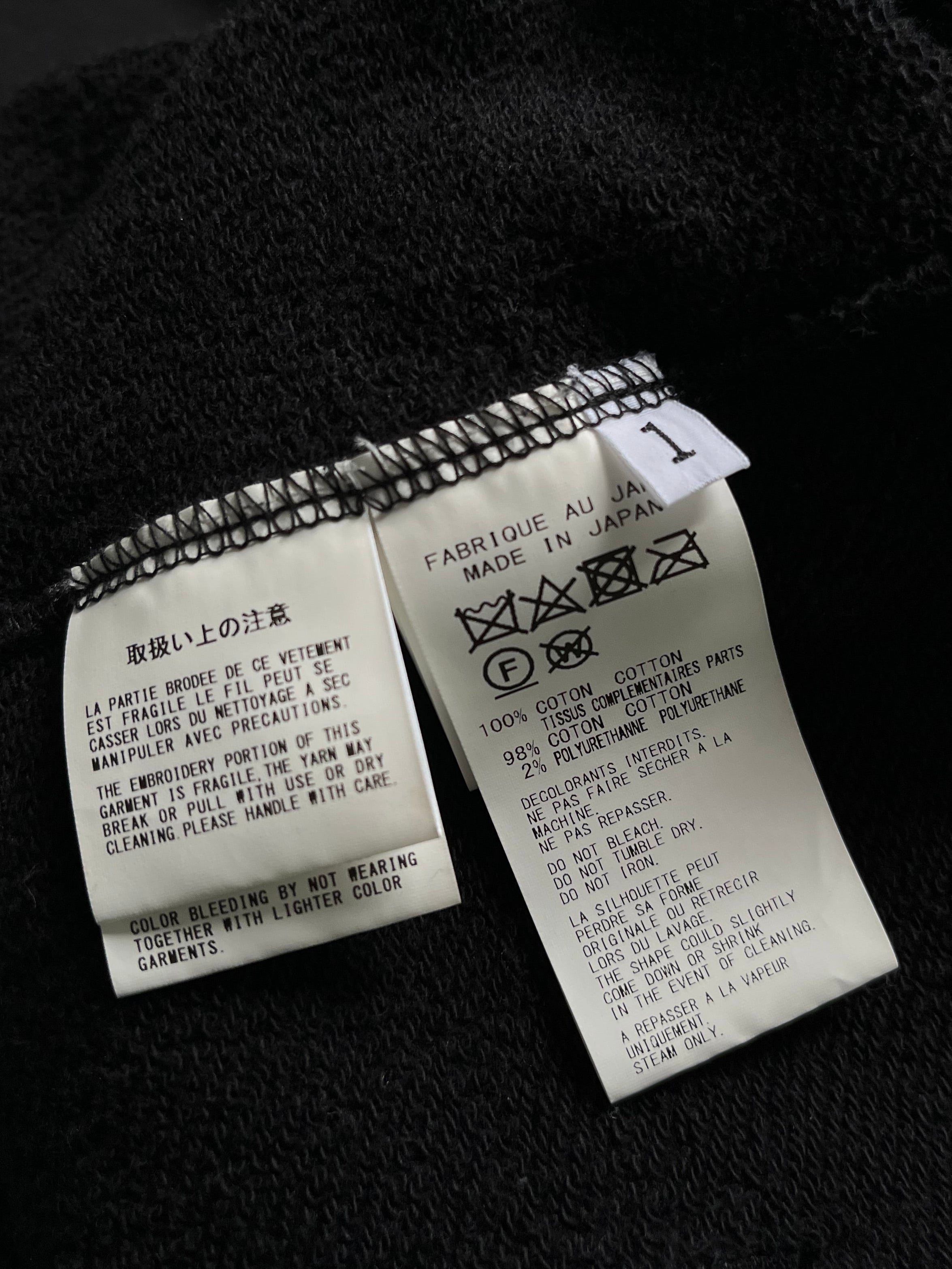 Yohji Yamamoto SS24 black signature hoodie with minimalist design and relaxed fit, displayed on a hanger.