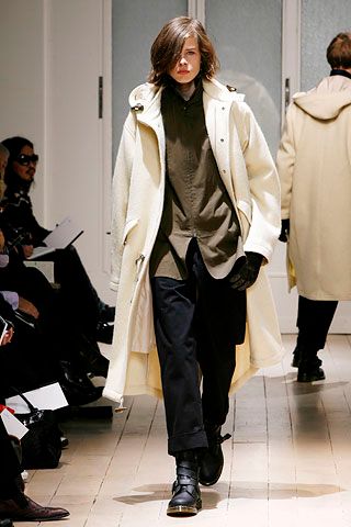 Yohji Yamamoto AW07 runway hooded wool duffel coat hanging on a rack, showcasing its textured fabric and oversized hood.